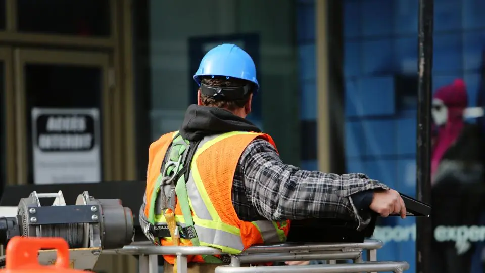 Técnico con chaleco reflectivo y casco operando un equipo en la calle