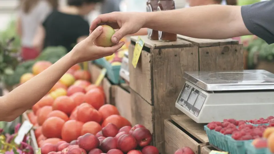Vendedora entregando fruta a un cliente en un puesto de mercado